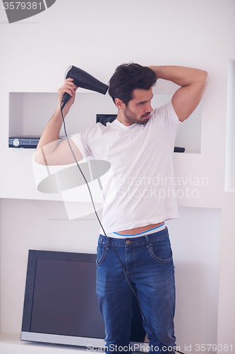 Image of handsome man using  hairdryer