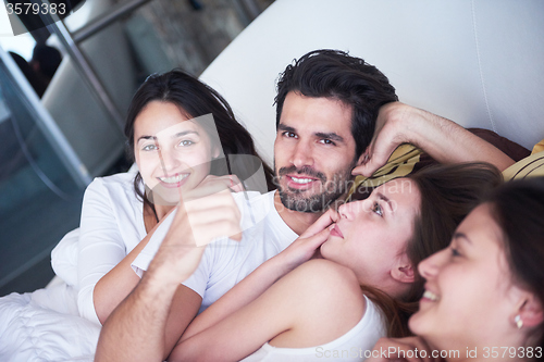 Image of handsome man in bed with three beautiful woman