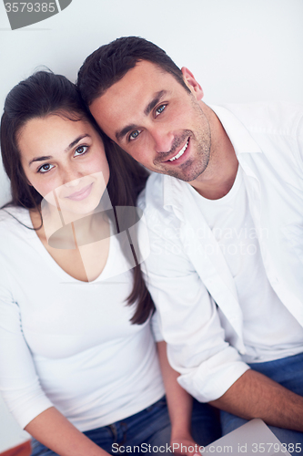 Image of relaxed young couple working on laptop computer at home