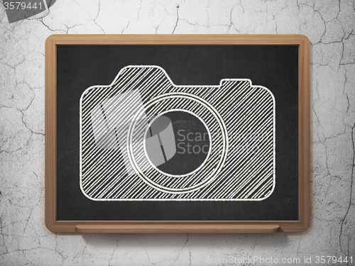 Image of Tourism concept: Photo Camera on chalkboard background