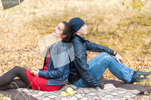 Image of Young romantic couple sits on plaid. Autumn picnic
