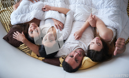 Image of handsome man in bed with three beautiful woman