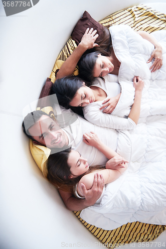 Image of handsome man in bed with three beautiful woman