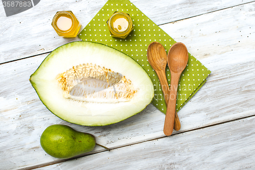 Image of Cut melon honey and green pear on wood