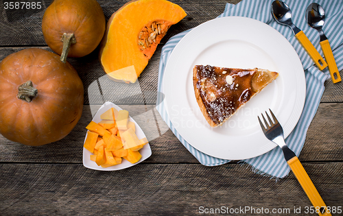 Image of Piece of pie and Pumpkin slices on wooden table