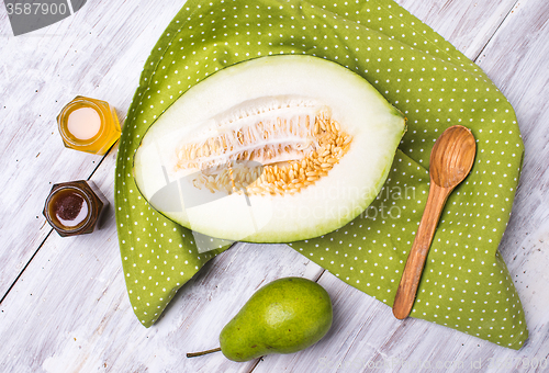 Image of tasty melon with honey and pears on wood