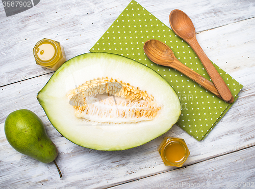 Image of Ripe melon with honey and pear on white wood