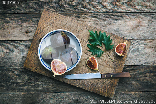 Image of Figs and knife on chopping board and wooden table