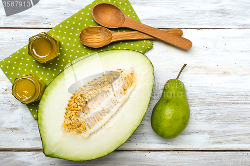 Image of Healthy melon green pear and honey on rustic wood