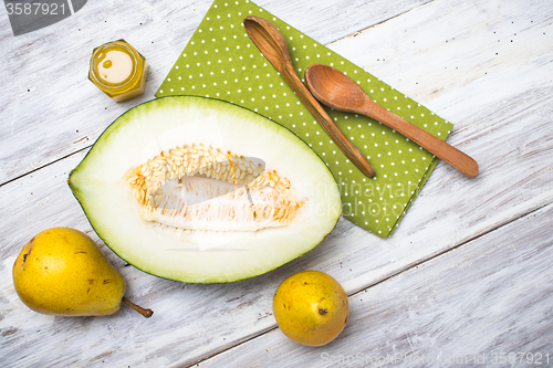 Image of tasty melon with honey and yellow pears on white wood