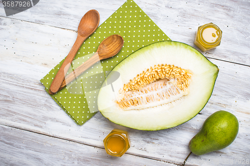 Image of Cut melon with honey and green pear on wood