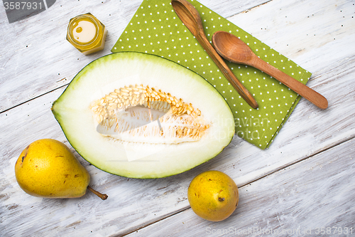 Image of Cut melon with honey and yellow pears on wood