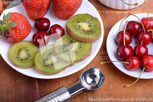 Image of fruit with cherry, strawberry, kiwi on wooden plate