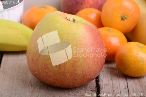 Image of Bananas apple mandarin peach strawberry on wooden background as health food concept