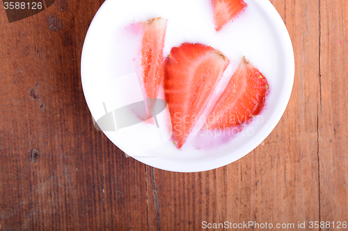 Image of Slice of pie with strawberry on white plate, milk drink, wooden background. Top view