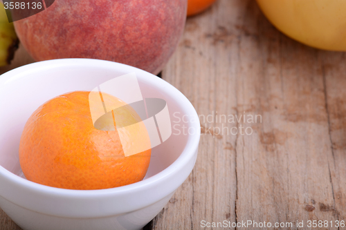 Image of Mandarin Apples Bananas Peach on wooden plate