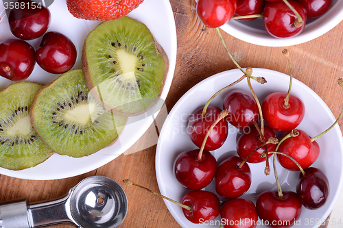 Image of fruit with cherry, strawberry, kiwi on wooden plate