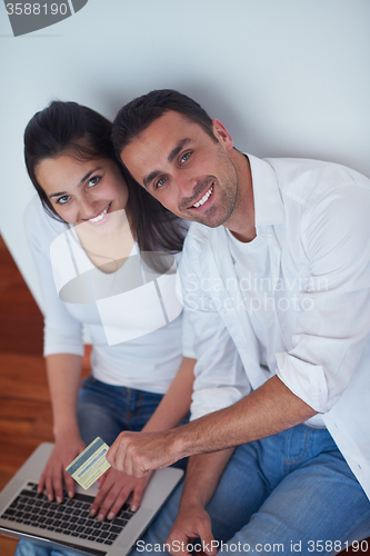 Image of relaxed young couple working on laptop computer at home