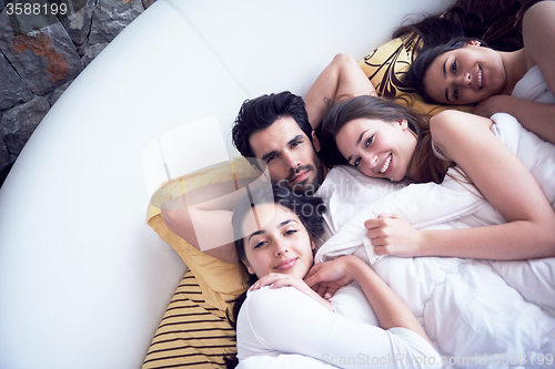 Image of handsome man in bed with three beautiful woman