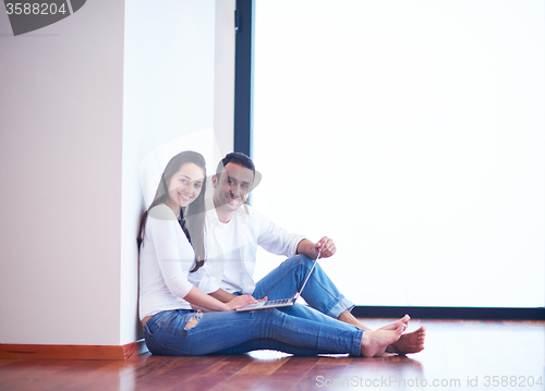 Image of relaxed young couple working on laptop computer at home