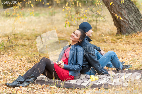 Image of Young romantic couple sits on plaid. Autumn picnic