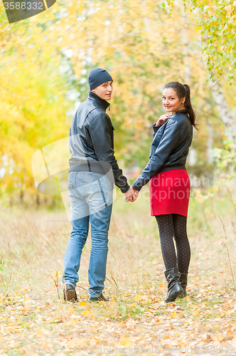 Image of Young romantic couple walks in autumn forest