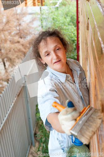 Image of Pretty woman paints her wooden house