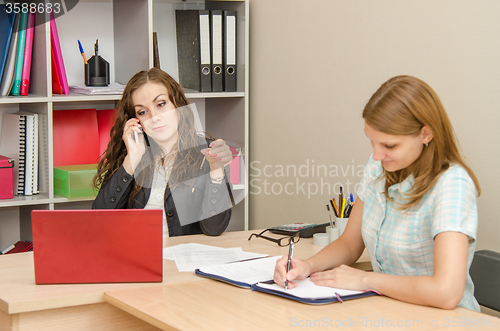 Image of Discouraged chairwoman talking on a cell phone, an employee of the office wrote in a document