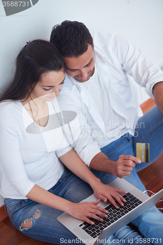 Image of relaxed young couple working on laptop computer at home