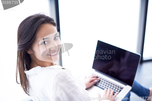 Image of relaxed young woman at home working on laptop computer