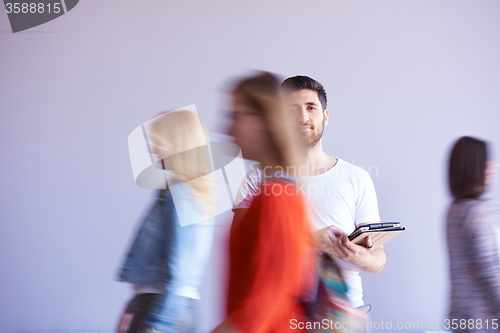 Image of student working on tablet, people group passing by