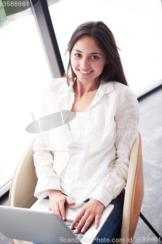 Image of relaxed young woman at home working on laptop computer