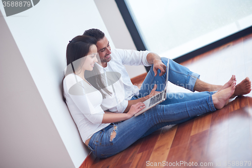 Image of relaxed young couple working on laptop computer at home