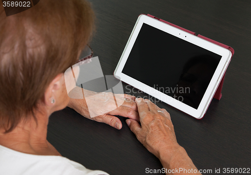 Image of Senior lady relaxing and reading the screen of her tablet