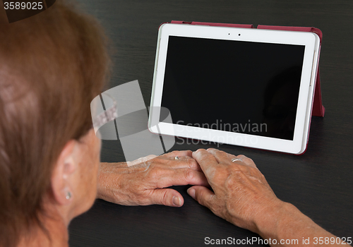 Image of Senior lady relaxing and reading the screen of her tablet