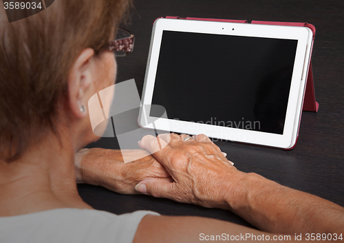 Image of Senior lady relaxing and reading the screen of her tablet