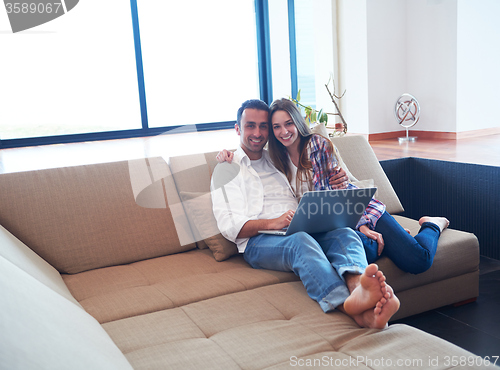 Image of relaxed young couple working on laptop computer at home