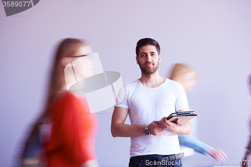 Image of student working on tablet, people group passing by