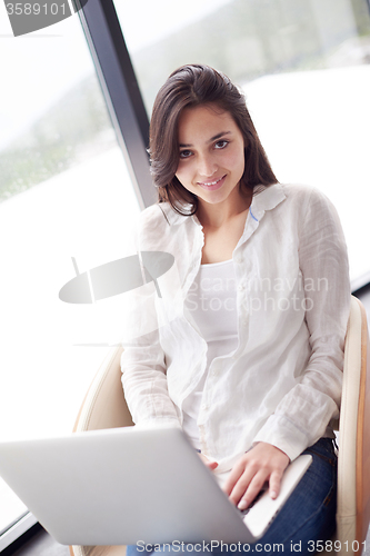 Image of relaxed young woman at home working on laptop computer