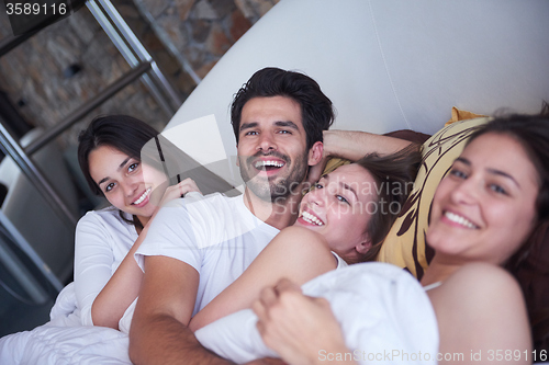 Image of handsome man in bed with three beautiful woman