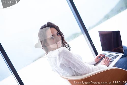 Image of relaxed young woman at home working on laptop computer