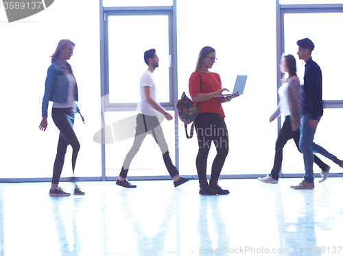 Image of student girl standing with laptop, people group passing by