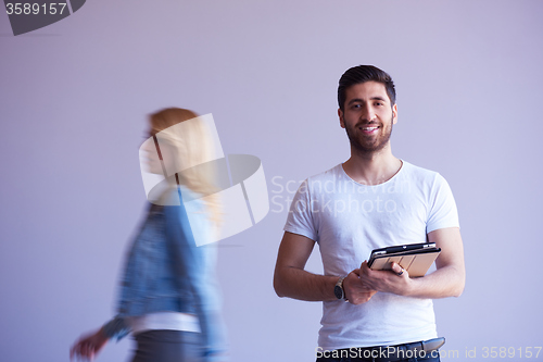 Image of student working on tablet, people group passing by