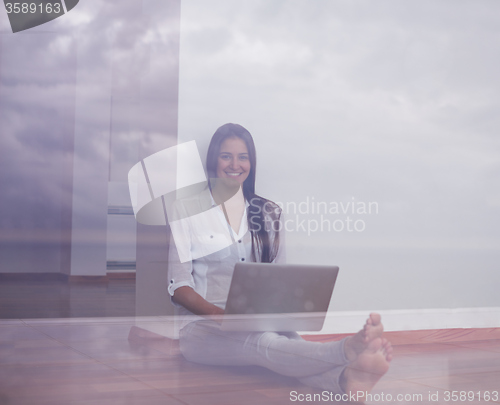 Image of relaxed young woman at home working on laptop computer