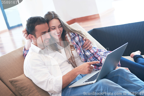 Image of relaxed young couple working on laptop computer at home