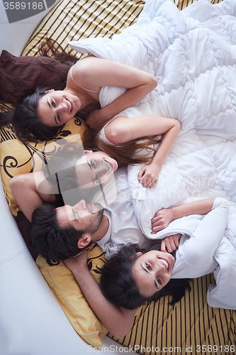 Image of handsome man in bed with three beautiful woman