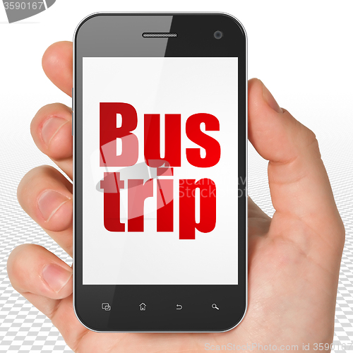 Image of Travel concept: Hand Holding Smartphone with Bus Trip on display