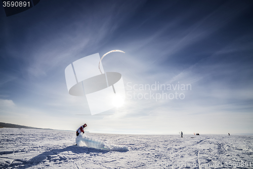 Image of Kiteboarder with blue kite on the snow