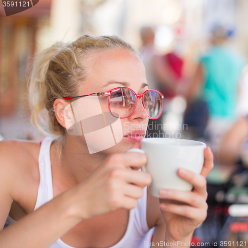 Image of Woman drinking coffee outdoor on street.