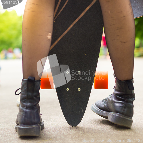 Image of Teenage girl urban long board riding.